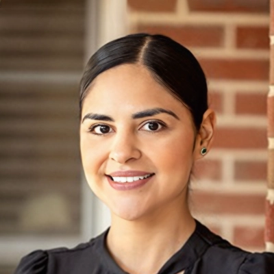 Office Manager Roxana Smiling In Front Of Brick Wall